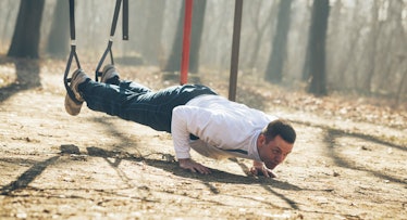 A man doing exercises with a playground swing set