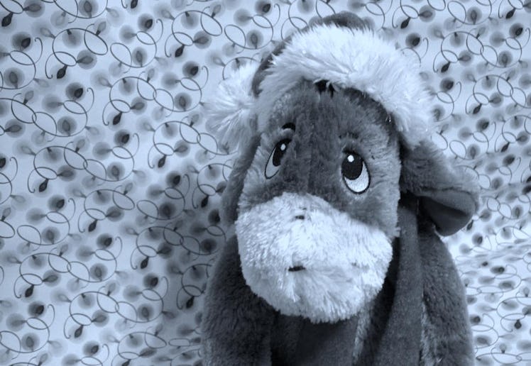 A sad-looking donkey stuffed animal wearing a Christmas hat.