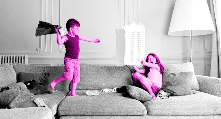 A boy throwing a pillow cover at his sister in the living room as she raises a laundry basket at him