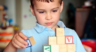 child in blue polo shirt plays with blocks