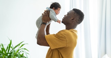 A father holds a baby while standing.