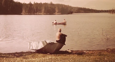 A man sitting on a boat that is on a beach next to water