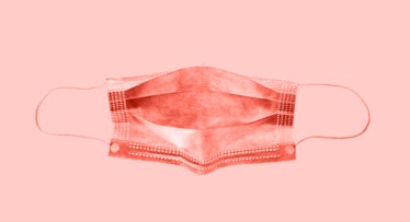 A red colored face mask in front of a pink background