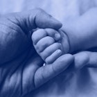 A father holding the hand of his stillborn daughter