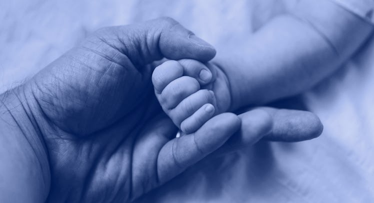A father holding the hand of his stillborn daughter