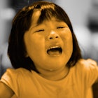 A crying toddler girl whose parents need to know how to discipline her with a yellow and grey color ...