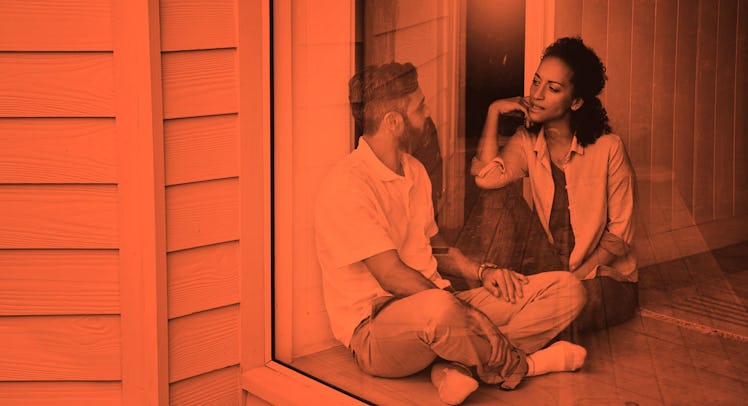 A man being vulnerable with his wife while they both sit in front of a large window