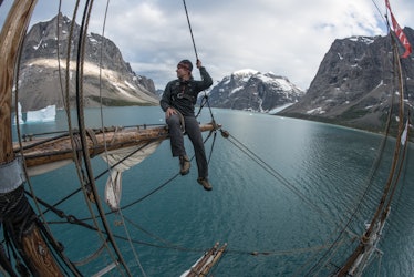 Mike Libecki on top of a ship with the sea and mountains in the background