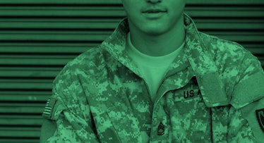 A man in a camo uniform stands in front of a wall. green color filter
