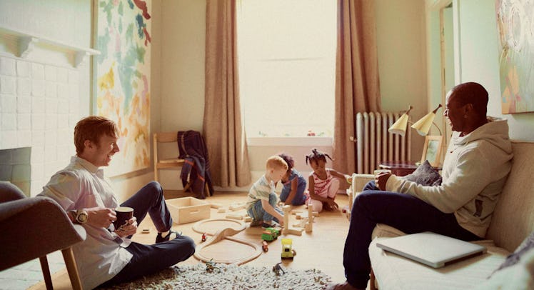 Two dad friends laughing while watching their children play