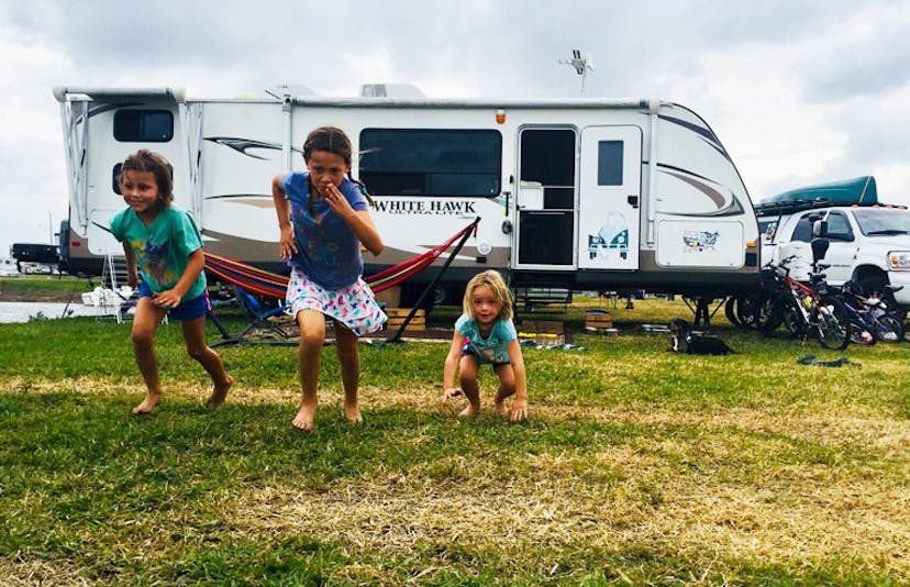 Three kids playing in front of an RV, all three of them are racing towards the camera