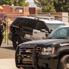 Two police cars and a police officer in front of a school building as school security