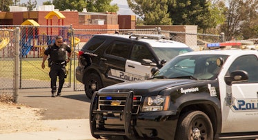 Two police cars and a police officer in front of a school building as school security