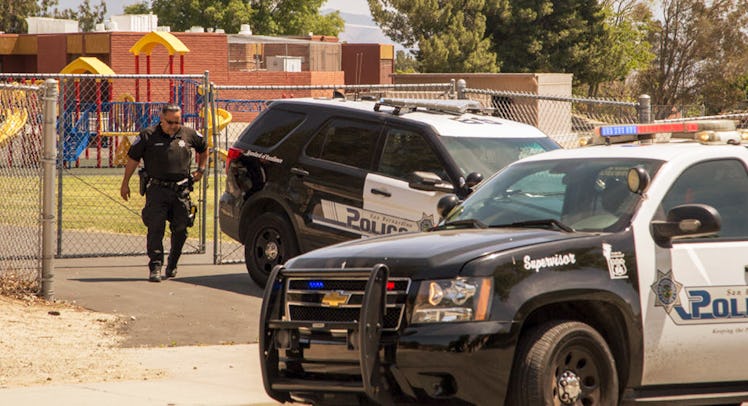 Two police cars and a police officer in front of a school