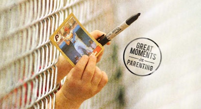 A young boy giving a baseball player card and a black marker for signing through a fence