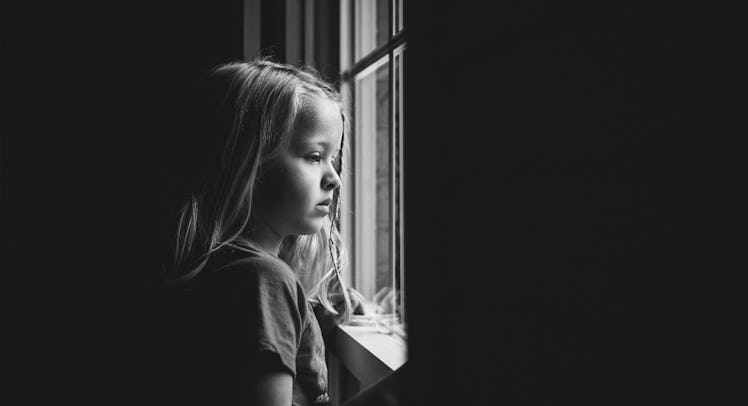 grey scale edit of a girl looking sadly out a window