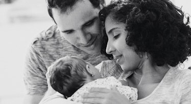 灰度编辑的母亲抱着新生儿和父亲看着她的肩膀崇拜