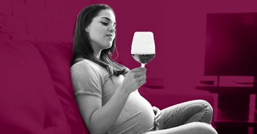 a pregnant woman stares at a glass of wine in her hand