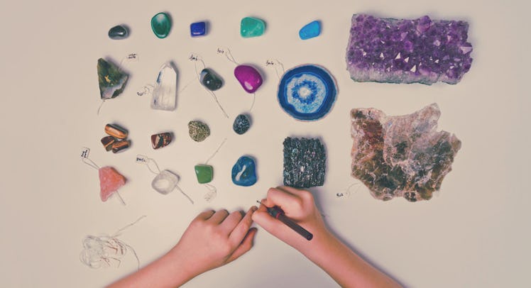 someone's hands carving the sides of a variety of birthstones on a table