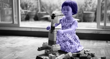 greyscale edit of 5-year-old girl playing blocks home alone