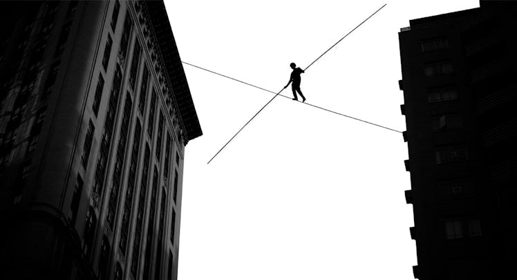 A man crossing a tight rope between two residential buildings