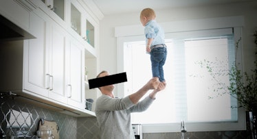 A dad balancing his baby on his extended hands.