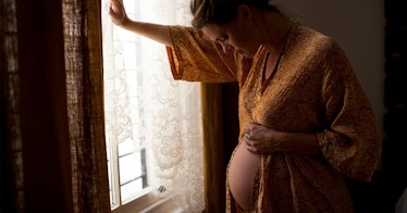 Pregnant woman breathing and leaning on a wall.