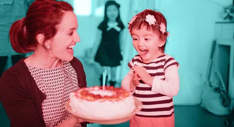 a 2-year-old in a flower crown at a kids birthday party excitedly blows out candles on a cake