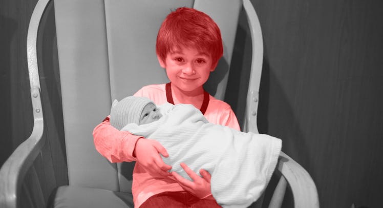 An older sibling holding his black and white newborn sibling in his lap