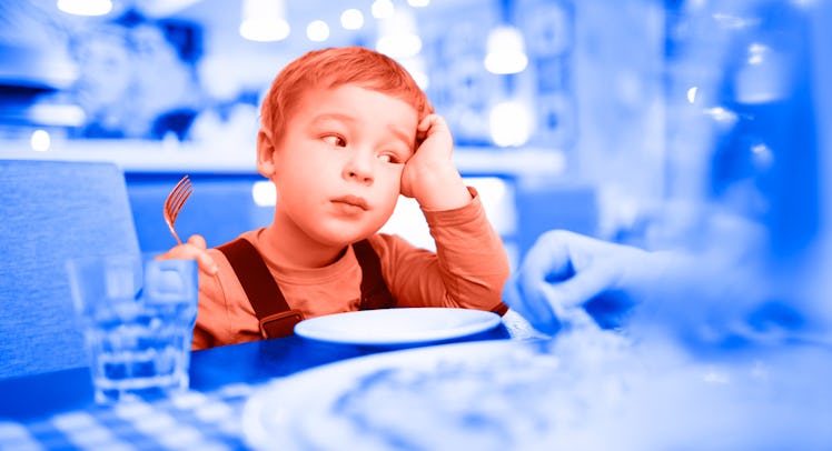 A bored kid sitting at a table at a restaurant in front of an empty plate with his head in his hand
