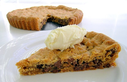 A piece of a cookie cake served on a plate with ice cream on it