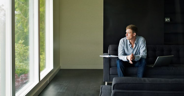 a man sitting alone in a living space stares out the window
