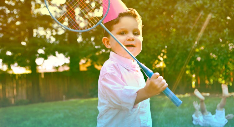 3-Year-Old playing badminton outdoors at a birthday party.