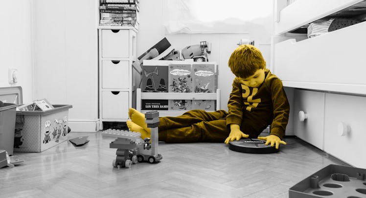A kid spending time alone in his bedroom, sitting on the floor, and playing with his toys