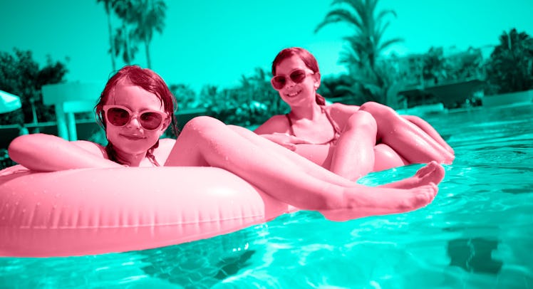 Kids playing with pink pool floats in a swimming pool