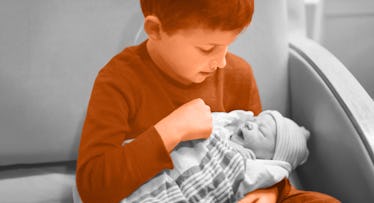 An older sibling sitting on a couch and holding a baby