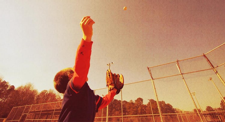 A kid catching a fly ball while wearing a baseball glove
