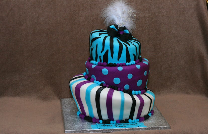 A topsy-turvy blue, black, purple, and white birthday cake