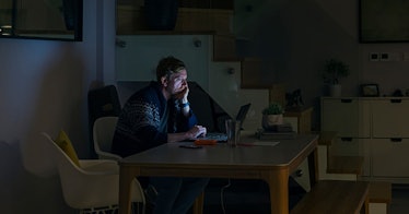 Man at table in dark room alone.