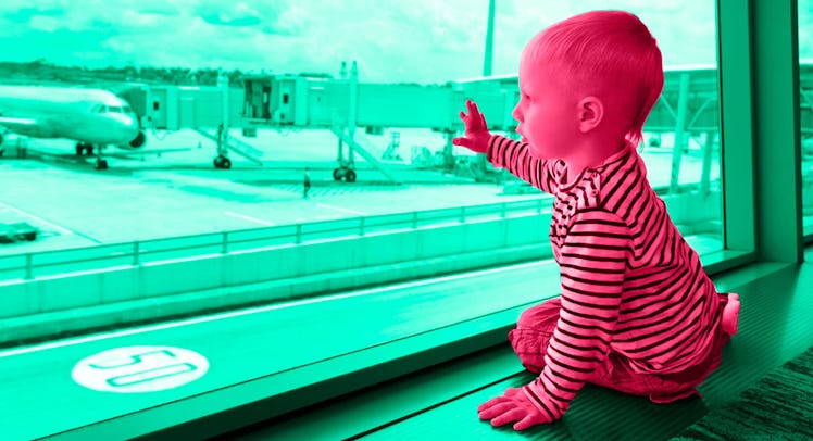A toddler sitting next to a window at the airport, looking out at the landing planes