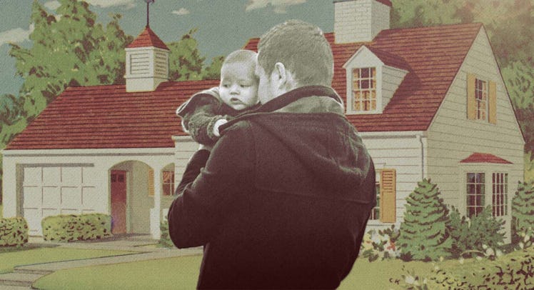 A father holding his toddler in front of a red roof and white wall house