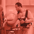 A dad using a baby carrier to hold his baby while he cleans the house. red color filter