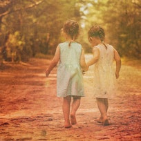 vintage-looking photo of young twin girls walking barefoot down a country lane