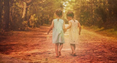 vintage-looking photo of young twin girls walking barefoot down a country lane