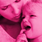 A mother holding a child with an open mouth and in pain because of canker sores