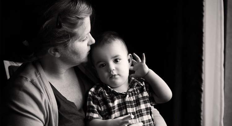 black and white photo of a toddler sitting in his mother's lap