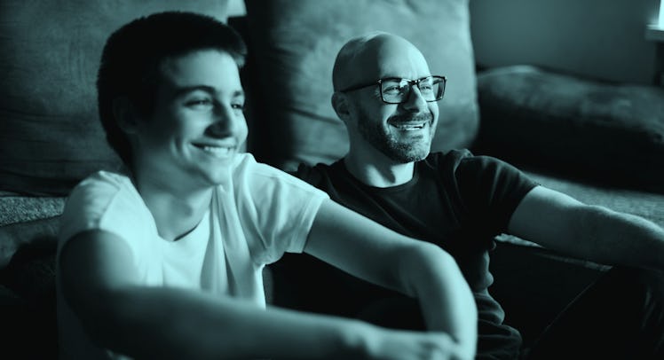 A father watching a movie with his teenage son