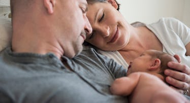 newborn baby girl restinig on father's chest next to mother