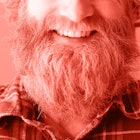 redscale edit of a headshot of a man with a beard smiling and wearing a flannel shirt