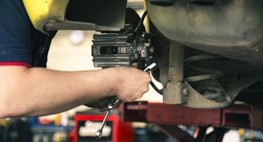 an auto mechanic works under the hood of a car